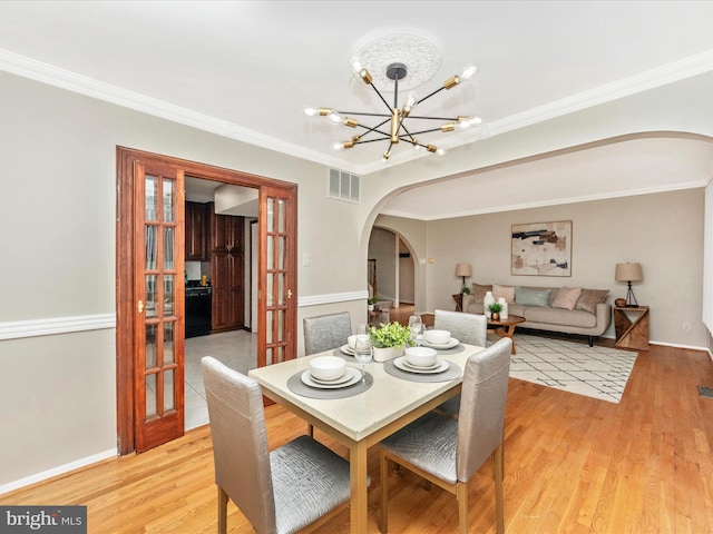 dining space featuring light hardwood / wood-style floors, crown molding, and french doors