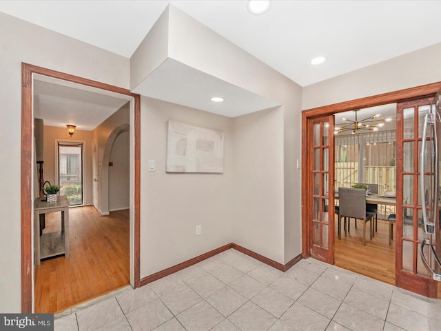 unfurnished room featuring a chandelier and light hardwood / wood-style flooring