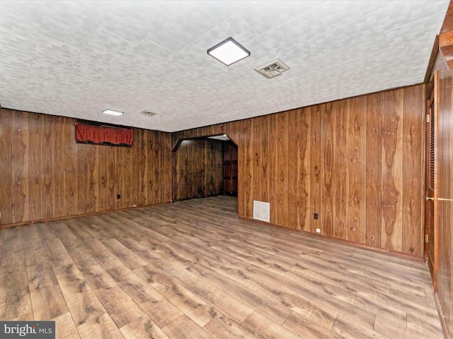 basement featuring wood-type flooring and wood walls