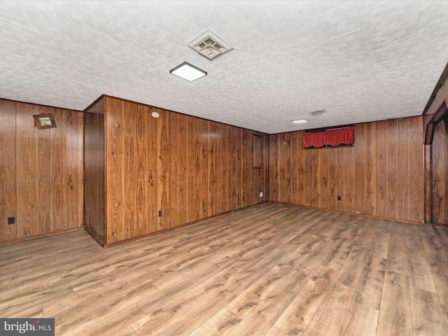 basement featuring wood-type flooring and wooden walls