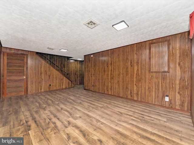 basement with hardwood / wood-style flooring and wooden walls