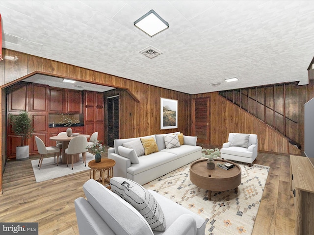 living room featuring light wood-type flooring and wooden walls