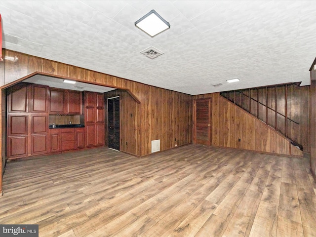 unfurnished living room featuring wooden walls and hardwood / wood-style flooring