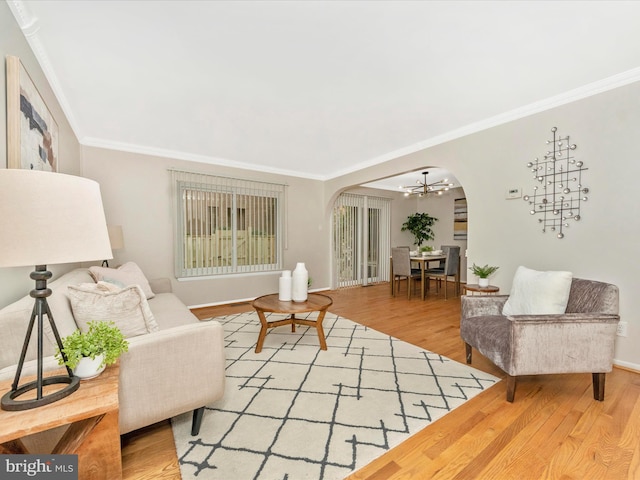 living room featuring hardwood / wood-style flooring, ornamental molding, and an inviting chandelier