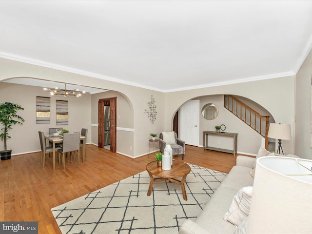 living room with ornamental molding, a notable chandelier, and hardwood / wood-style flooring