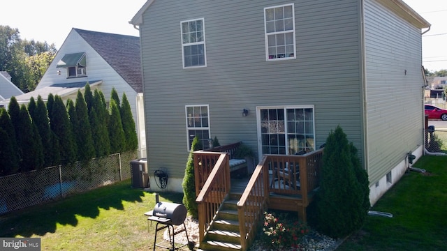 rear view of property featuring a yard, cooling unit, and a deck