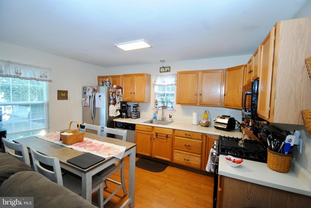 kitchen featuring light hardwood / wood-style flooring, black appliances, and sink