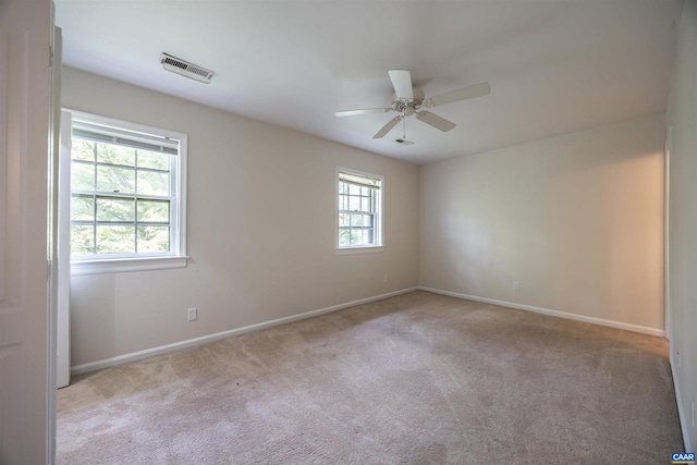 carpeted spare room featuring ceiling fan and a wealth of natural light