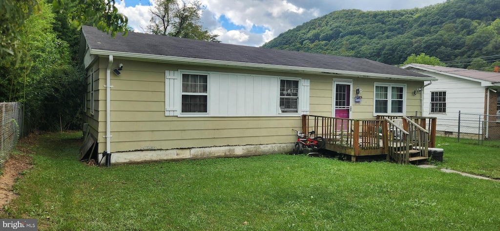 view of front of home featuring a deck with mountain view and a front lawn