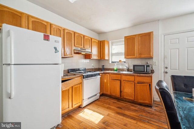 kitchen with wood-type flooring, sink, white appliances, and decorative backsplash