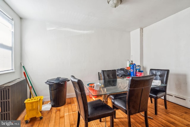 dining area with radiator, hardwood / wood-style floors, and a baseboard heating unit