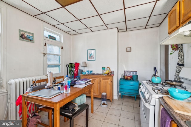 tiled dining area featuring radiator and a paneled ceiling