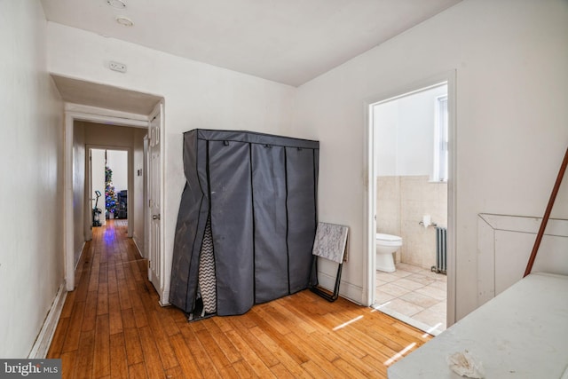 bathroom featuring wood-type flooring, tile walls, radiator, and toilet