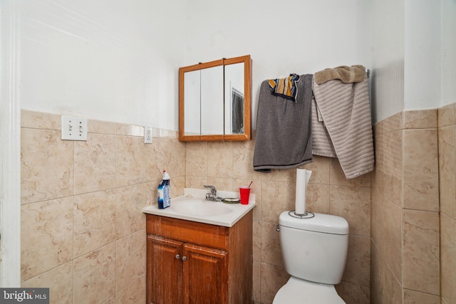 bathroom with vanity, tile walls, and toilet