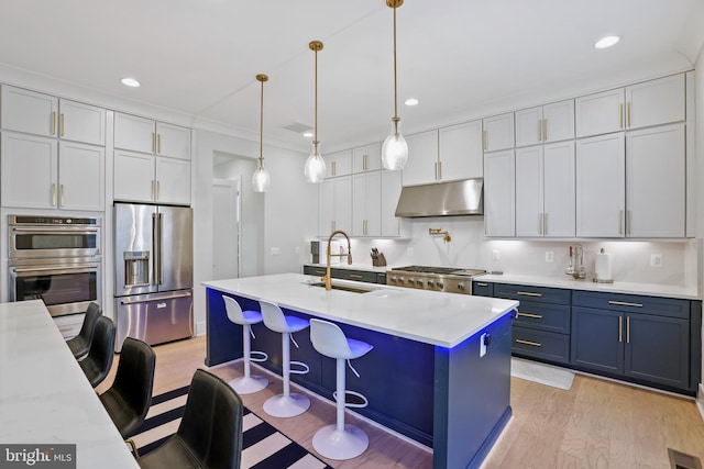 kitchen with a breakfast bar, sink, appliances with stainless steel finishes, an island with sink, and pendant lighting