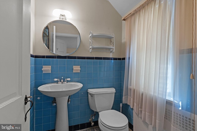 bathroom featuring tile walls, toilet, and lofted ceiling