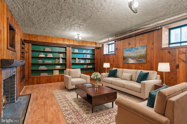 living room featuring hardwood / wood-style flooring, built in features, wood walls, and a textured ceiling