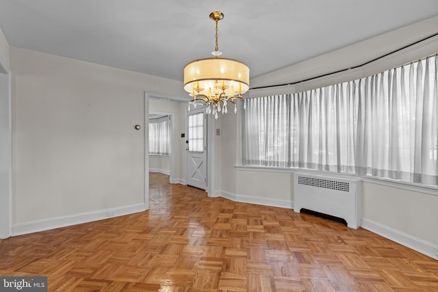 unfurnished dining area featuring a notable chandelier, light parquet floors, and radiator heating unit