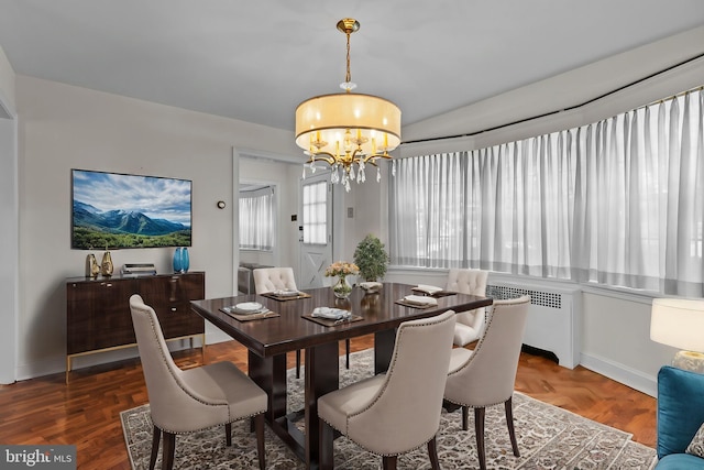 dining room with radiator, dark parquet flooring, and an inviting chandelier