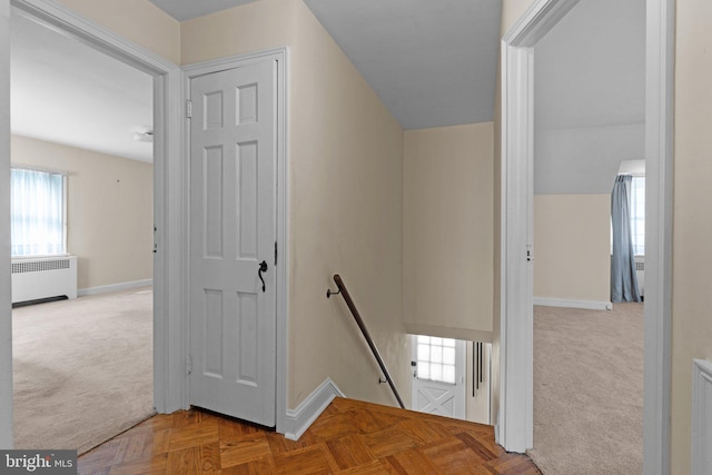 stairs with carpet floors, vaulted ceiling, and radiator heating unit