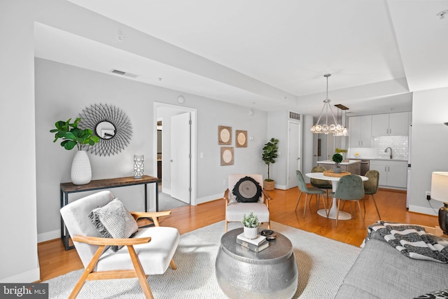 living room with light hardwood / wood-style flooring, a notable chandelier, and sink