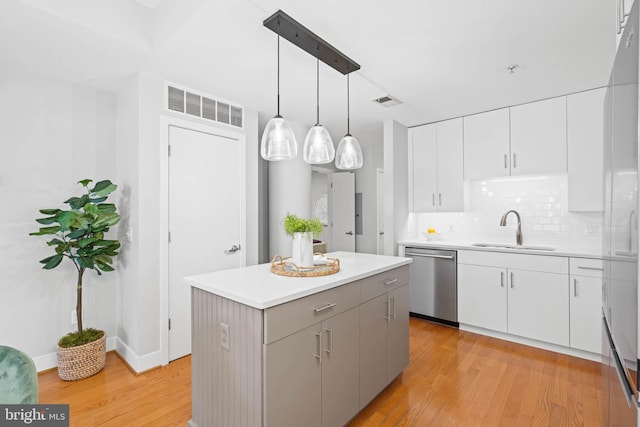 kitchen with pendant lighting, a center island, sink, stainless steel dishwasher, and light hardwood / wood-style floors