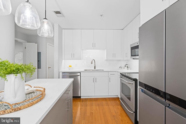 kitchen with white cabinets, decorative light fixtures, stainless steel appliances, and sink