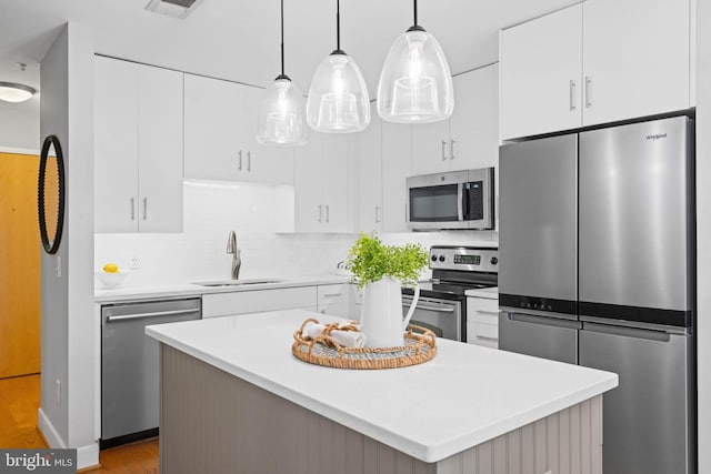 kitchen with white cabinetry, sink, hanging light fixtures, stainless steel appliances, and tasteful backsplash