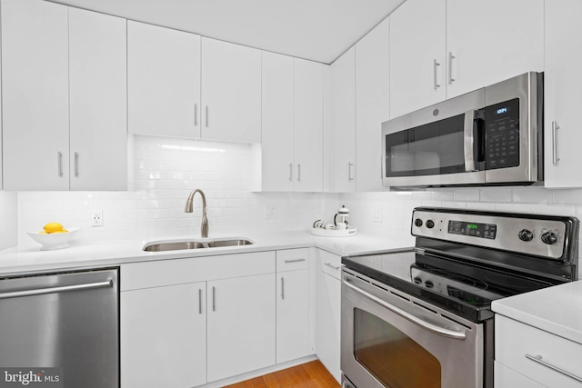 kitchen with decorative backsplash, white cabinetry, sink, and stainless steel appliances