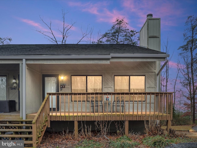 back house at dusk with cooling unit and a wooden deck