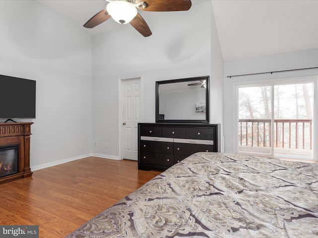 bedroom featuring ceiling fan, hardwood / wood-style flooring, access to exterior, and high vaulted ceiling