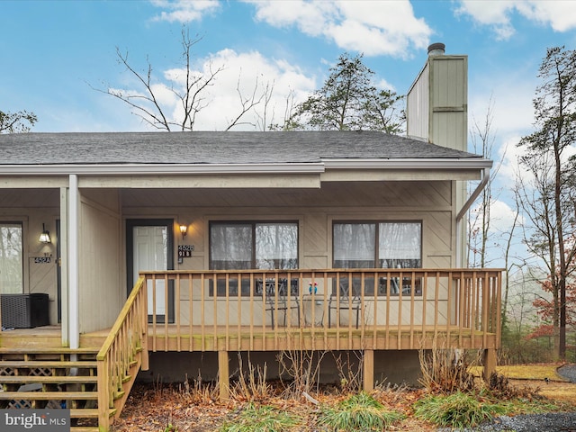 rear view of property featuring a wooden deck and cooling unit