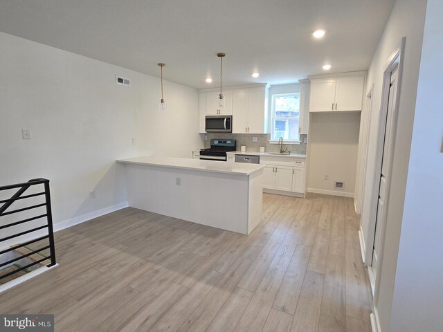 kitchen with white cabinets, light hardwood / wood-style floors, hanging light fixtures, and black range oven