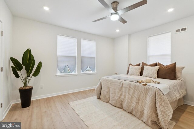 bedroom with light wood-type flooring, multiple windows, and ceiling fan