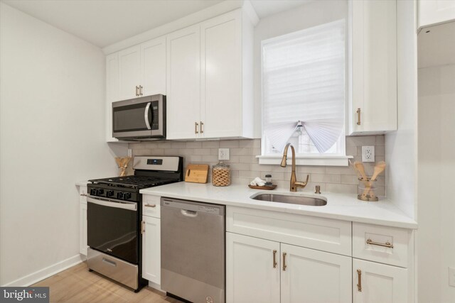 kitchen with decorative backsplash, white cabinetry, appliances with stainless steel finishes, and sink