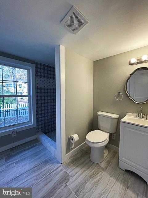 bathroom featuring vanity, toilet, and walk in shower