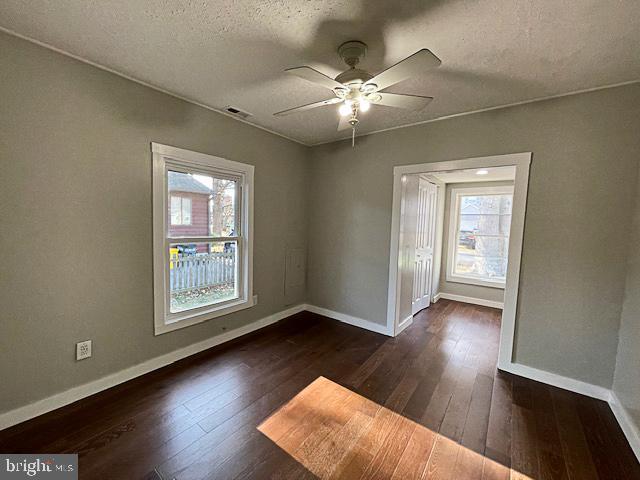 empty room featuring a textured ceiling, ceiling fan, and dark hardwood / wood-style floors