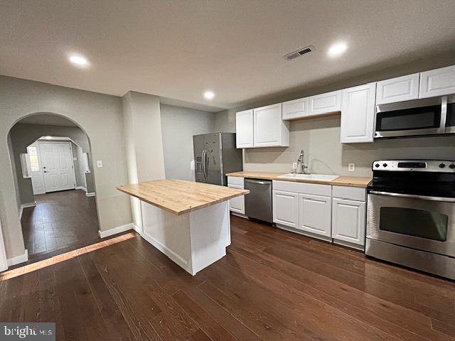 kitchen featuring wood counters, dark wood-type flooring, white cabinets, sink, and appliances with stainless steel finishes