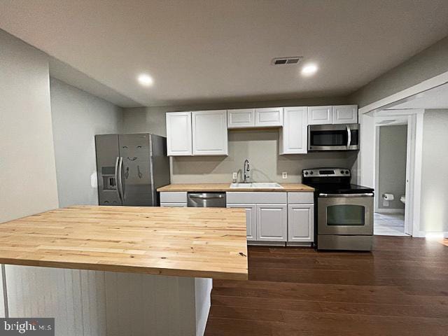 kitchen with sink, white cabinets, dark wood-type flooring, and appliances with stainless steel finishes