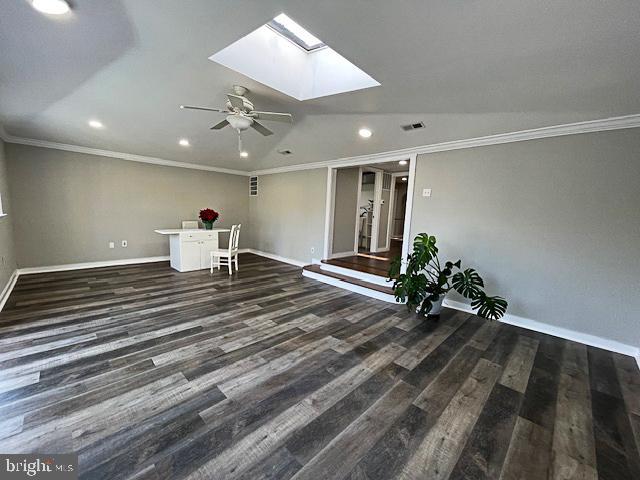 interior space with dark hardwood / wood-style floors, ceiling fan, crown molding, and vaulted ceiling with skylight