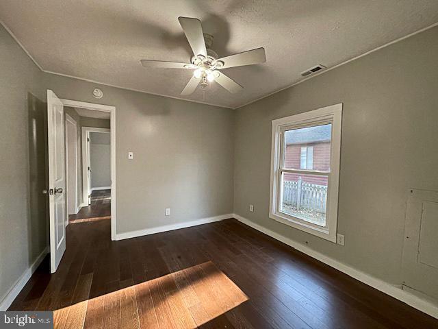 empty room featuring a textured ceiling, dark hardwood / wood-style floors, and ceiling fan