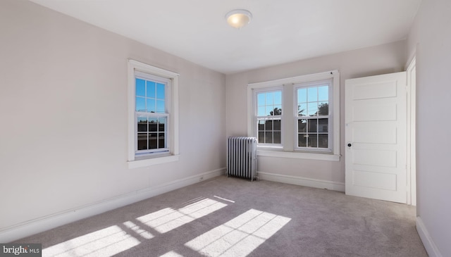 unfurnished room with light colored carpet and radiator heating unit