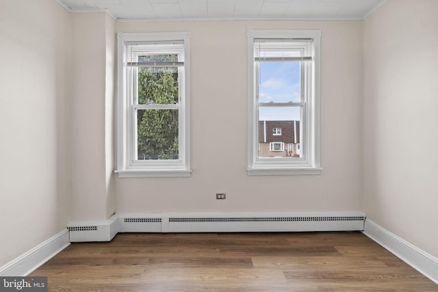 spare room with baseboard heating and wood-type flooring