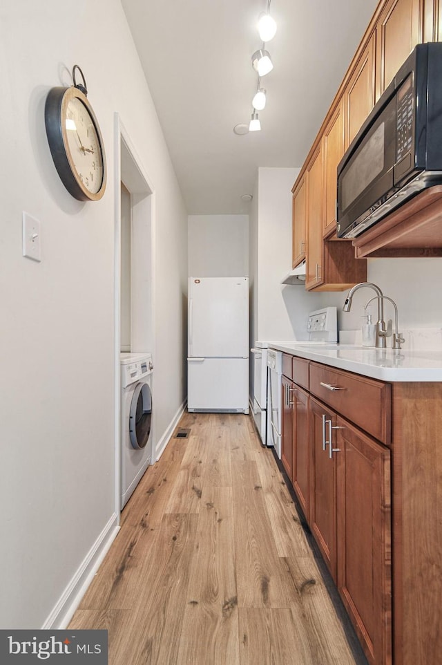 kitchen featuring washer / dryer, sink, white refrigerator, light hardwood / wood-style floors, and stove