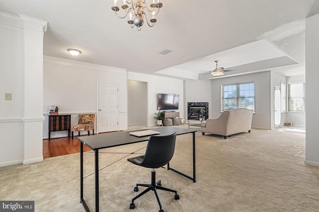 home office featuring light carpet, a tray ceiling, ceiling fan with notable chandelier, and a premium fireplace