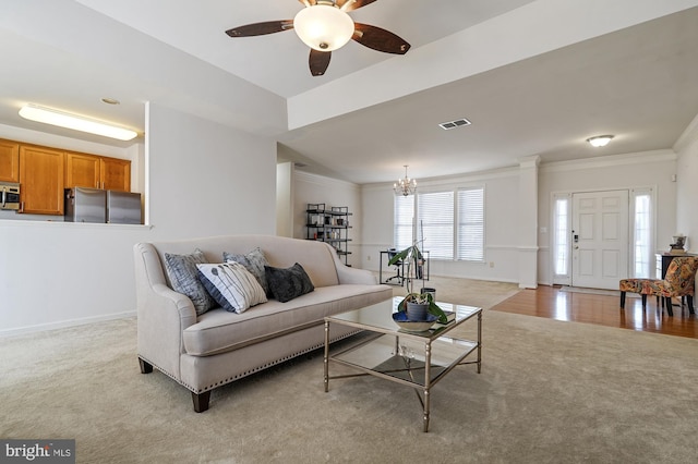 carpeted living room featuring crown molding and ceiling fan with notable chandelier