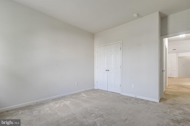 unfurnished bedroom featuring light colored carpet and a closet