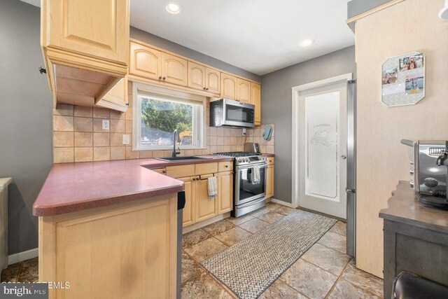 kitchen with appliances with stainless steel finishes, light brown cabinetry, sink, and backsplash