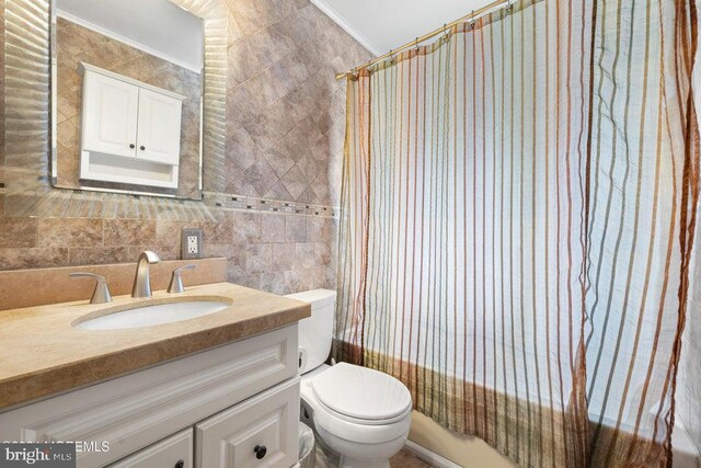 full bathroom featuring shower / tub combo with curtain, vanity, tile walls, ornamental molding, and toilet