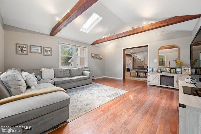 living room featuring hardwood / wood-style floors and lofted ceiling with skylight